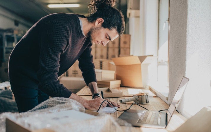 Man writing notes in the diary while standing at his workplace.